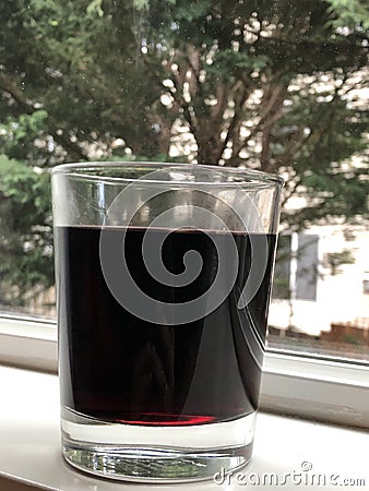 A red wine glass over the window with green background Stock Photo