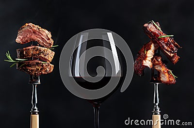 Red wine and grilled meat. Grilled pork belly and beef steak with rosemary on a black background Stock Photo