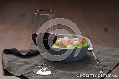 Red wine in thin wine glass with salad in blue bowl Stock Photo