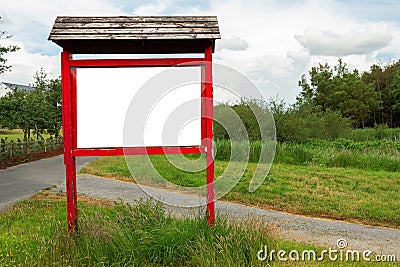 Red wooden billboard with clean white space for text in a park on green grass by a small walking path Stock Photo