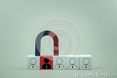 Red wooden block with an icon of one person and a magnet selects one candidate from the row of employees Stock Photo