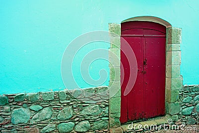 Red wooden door on the concrete and stone wall in aqua blue color Stock Photo