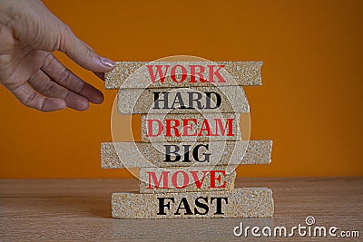 Red words Work hard dream big move fast on brick blocks on a beautiful orange background. Businessman hand. Business, motivational Stock Photo