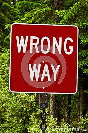 A red wrong way sign against trees Stock Photo