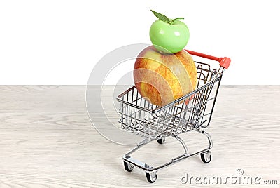 Red and Yellow Apple and Ceramic Green Apple in a Miniature Shopping Cart Stock Photo