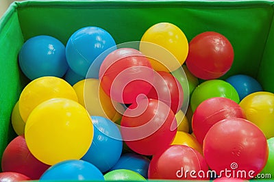 Red, yellow, blue plastic balls lie in the green box. The interior of the children`s room with lots of colorful toys. Stock Photo