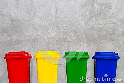 Red, Yellow, Green and Blue Recycle Bins. Concrete wall background. Stock Photo