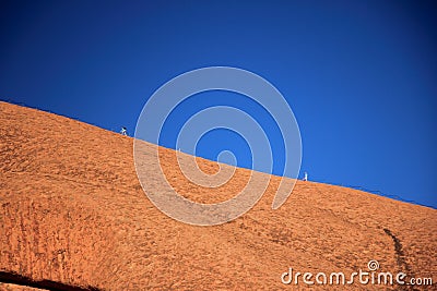 The reddish stone surface of Ayers Rock with two climbing ir. Editorial Stock Photo