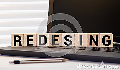 REDESIGN word written on wood cube with red background Stock Photo