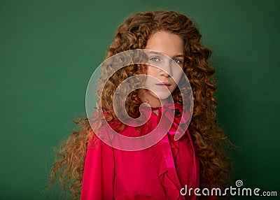 Redhair beautiful girl with curly afro curls in bright pink blouse on green background. Curly hair care, freckle cream, teen book Stock Photo