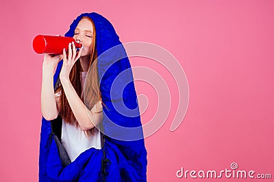 Redhair ginger woman holding red thermos and wrapped in in sleeping bag Stock Photo