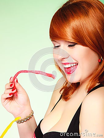 Redhair girl holding sweet food jelly candy on green. Stock Photo