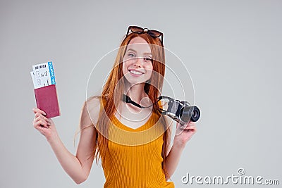 Redhaired ginger happy female dream tourist with boarding passand camera on white background studio Stock Photo