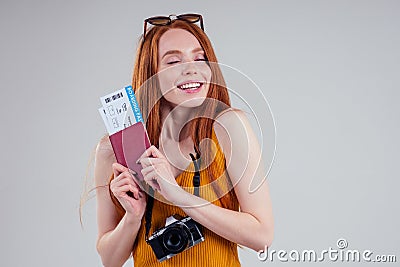 Redhaired ginger happy female dream tourist with boarding passand camera on white background studio Stock Photo