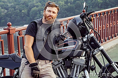 Redhead biker with beard in leather jacket and his bike. Stock Photo