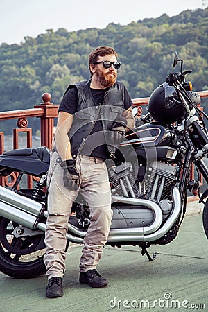 Redhead biker with beard in leather jacket and his bike. Stock Photo