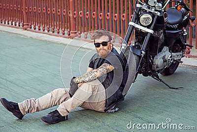 Redhead biker with beard in leather jacket and his bike. Stock Photo