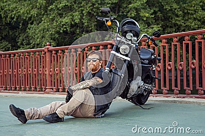 Redhead biker with beard in leather jacket and his bike. Stock Photo