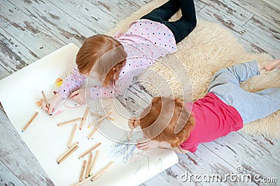 Children draw with colored pencils lying on the floor Stock Photo