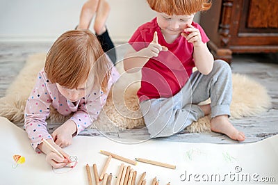 Children draw with pencils lying down and sitting on the floor Stock Photo