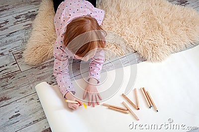 Girl draws with colored pencils, lying on the floor Stock Photo