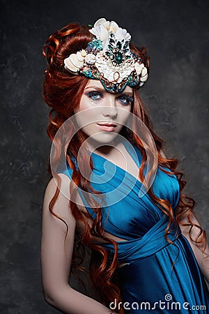 Redhead girl fabulous look, blue long dress, bright makeup and big eyelashes. Mysterious fairy woman with red hair. Big eyes Stock Photo