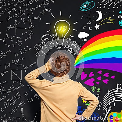 Redhead kid boy with lightbulb scetch on blackboard background. Brainstorming, idea and choice concept Stock Photo