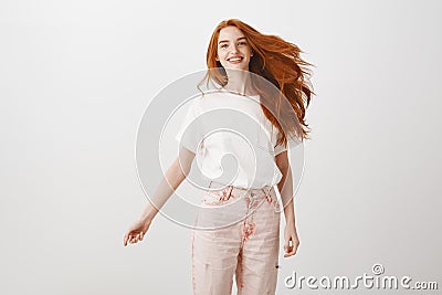 Redhead rule world. Portrait of carefree happy and charming female with ginger hair, jumping joyfully over gray Stock Photo