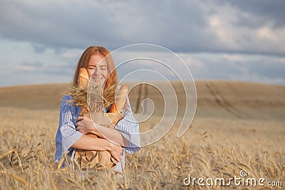Redhead woman with bakery products in ripe wheat field Stock Photo