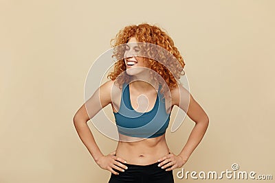 Redhead Woman. Fit Girl Portrait. Smiling Beautiful Female In Sportswear Keeping Hands On Hips. Stock Photo