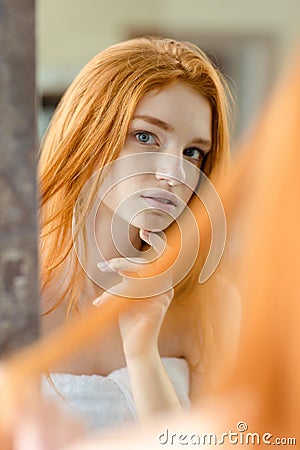 Redhead woman looking at her reflection in mirror Stock Photo