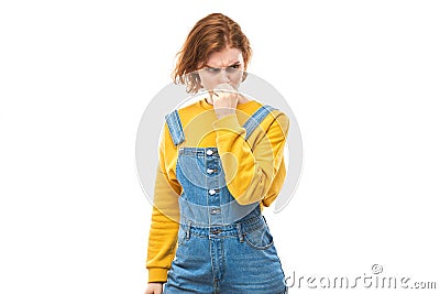 Redhead young woman holding nose to avoid disgusted smell, pinches nose and mouth with fingers and holding breath Stock Photo