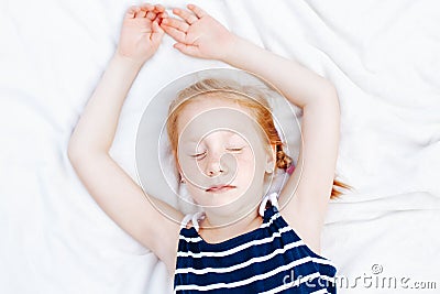 redheaded Caucasian child girl in striped nautical sleeveless shirt sleeping Stock Photo