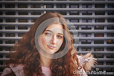 Redheaded girl looks at the camera with a calm expression on her tender face, pulling down her chin a little bit, posing Stock Photo