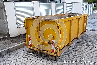 Reduced size of small and narrow yellow metal dumpsters container, construction trash, street reconstruction Stock Photo