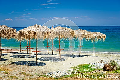 Reed umbrellas at empty beach Stock Photo