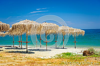 Reed umbrellas at empty beach Stock Photo