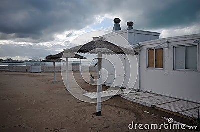 Reed umbrellas on empty beach during quarantine in Mar del Plata. Coastline with temporarily out of service tourist infrastructur Stock Photo