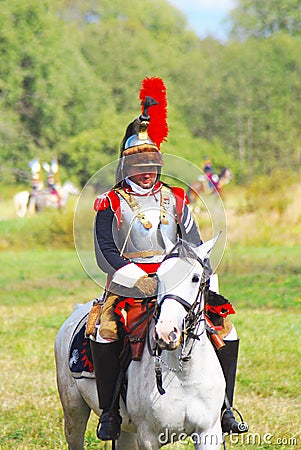 Reenactor-cuirassier dressed as Napoleonic war soldier rides a horse. Editorial Stock Photo