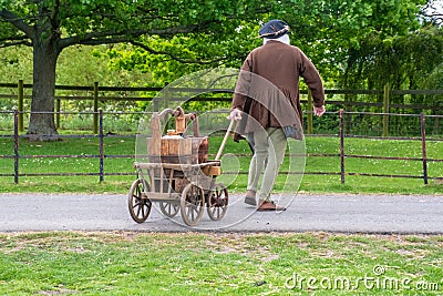 Reenactor in medieval costume pulling medieval drinks cart Stock Photo