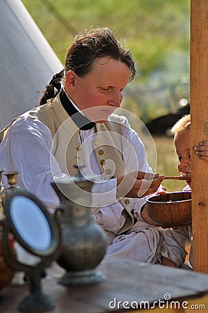 Reenactor woman feeds a child at Borodino battle historical reenactment in Russia Editorial Stock Photo