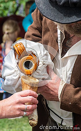 Reereenactor in medieval costume pouring a drink in horn cup Editorial Stock Photo