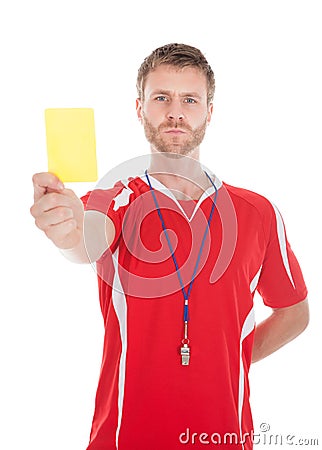 Referee blowing whistle while showing yellow card Stock Photo