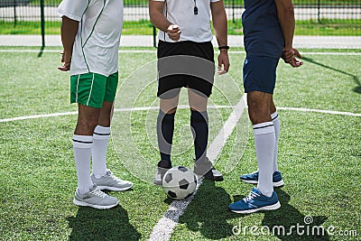 Referee and soccer players on soccer pitch starting game Stock Photo