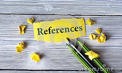 REFERENCES - word on a yellow tattered piece of paper with pencils and crumpled paper lumps on a light wooden background Stock Photo