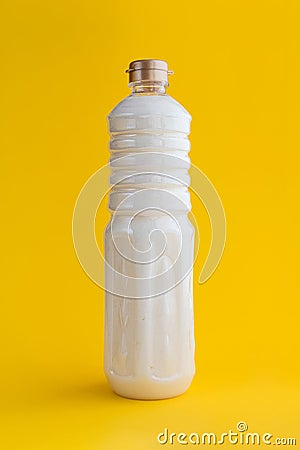 Refined cured white coconut fat in a bottle on a yellow background Stock Photo