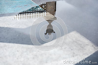 Reflection of Decorative historic metal fence in puddle after rain. Mysterious abstract, gate entrance in dreams Stock Photo