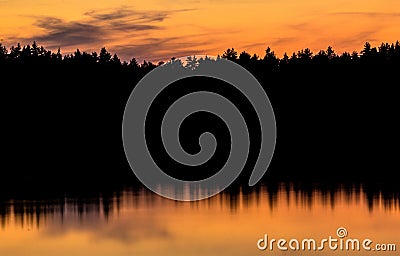 Reflection of forrest in the water, sunset silhouette, golden ho Stock Photo
