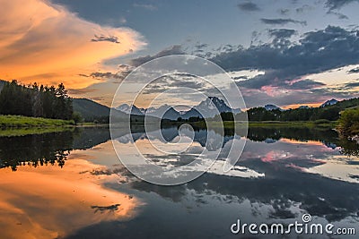 Reflection of Grand Tetons in Jackson Lake at sunset with beautiful clouds Stock Photo
