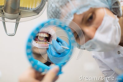Reflection in the mirror woman dentist doing teeth checkup man patient Stock Photo